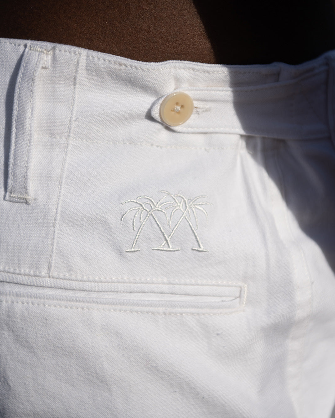 Natural corozo buttons on adjustable waist tab on Mens Linen Shorts in CLASSIC WHITE back, designer Lotty B for Pink House Mustique