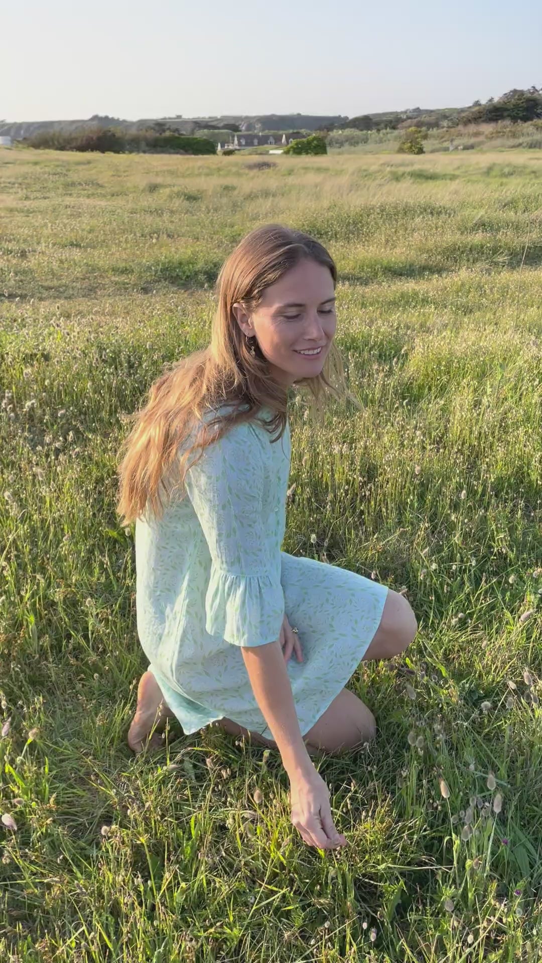 Video shows model Hettie picking wildflowers in a grassy meadow on a summer evening in a Pink House favorite - the Decima dress - a comfortable, breezy dress featuring an open V neckline with an elegant mandarin collar and 3/4 length sleeves with gathered cuffs.