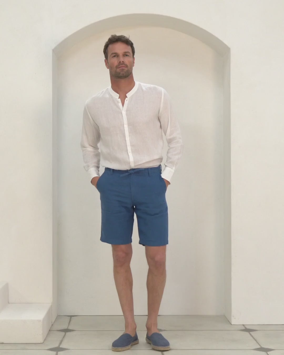 Video shows men's pure linen casual shorts in mid blue styled with a collarless white linen shirt by Pink House